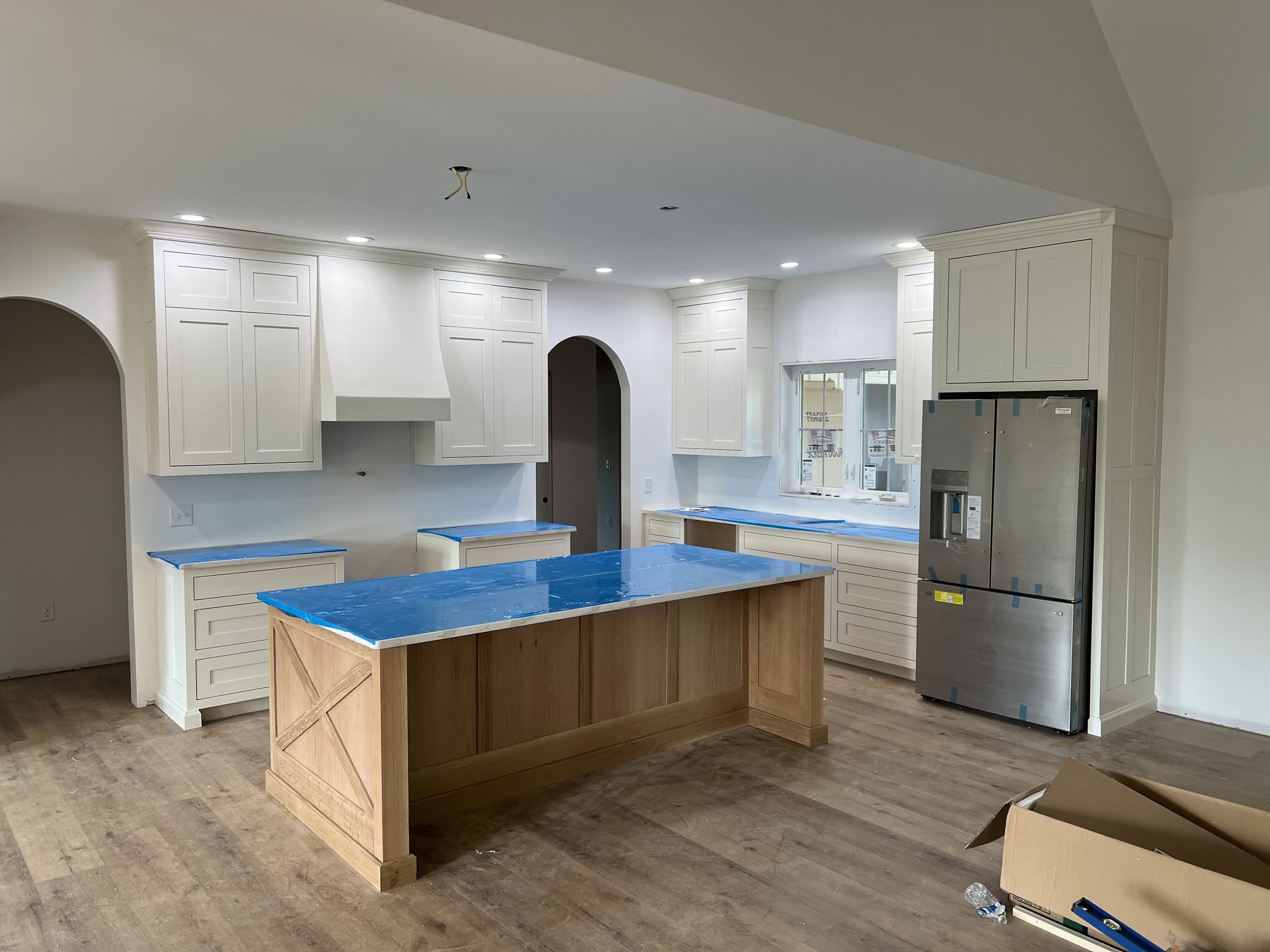 White kitchen cabinetry surrounding a natural wood island